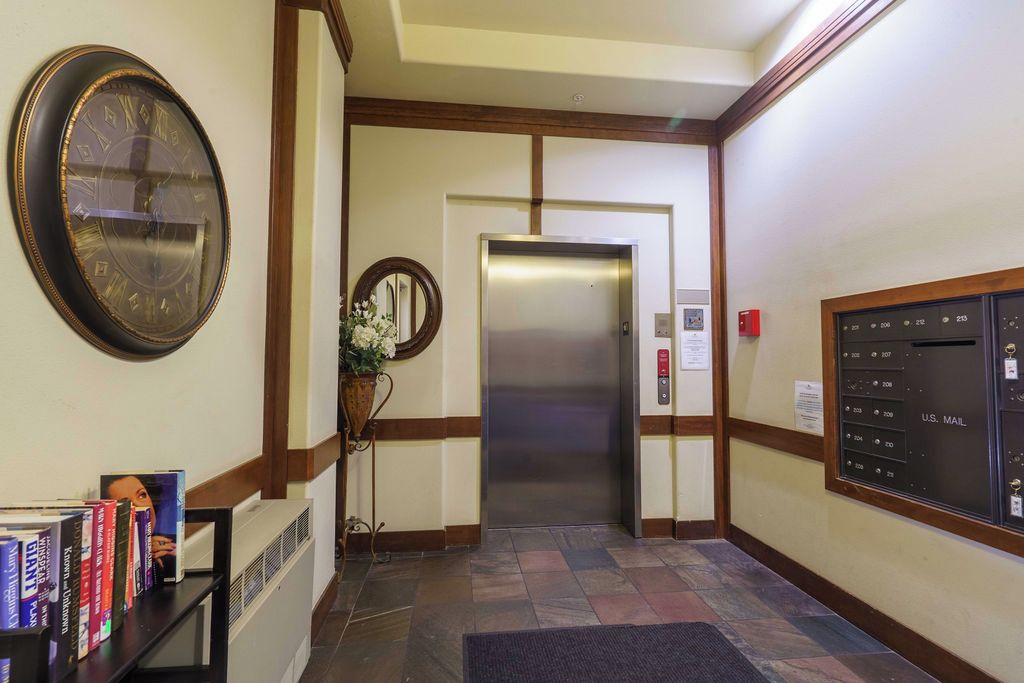 A hotel lobby with a reception desk, a clock, an elevator, and a mail slot.