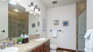 A bathroom with two sinks, a toilet, a large mirror, and a shower area. - Stylish, fully equipped 2-bed / 2-bath condo in Riverstone Village (Coeur d'Alene)