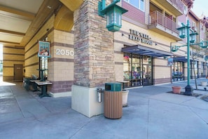 A building with a stone facade, a storefront with a sign reading 'The Well-Red Moose,' and outdoor seating with tables and chairs. - Stylish, fully equipped 2-bed / 2-bath condo in Riverstone Village (Coeur d'Alene)