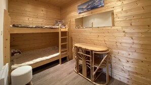 Una habitación de cabaña de madera con literas, una mesita y una silla.