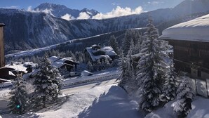 Un pueblo nevado en la montaña con casas de madera tradicionales, cielo despejado y vistas a picos lejanos.
