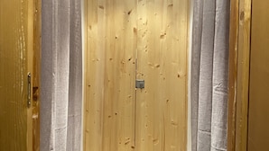 Una puerta de madera con dos manijas, una lámpara encima y una pequeña placa metálica en el centro.