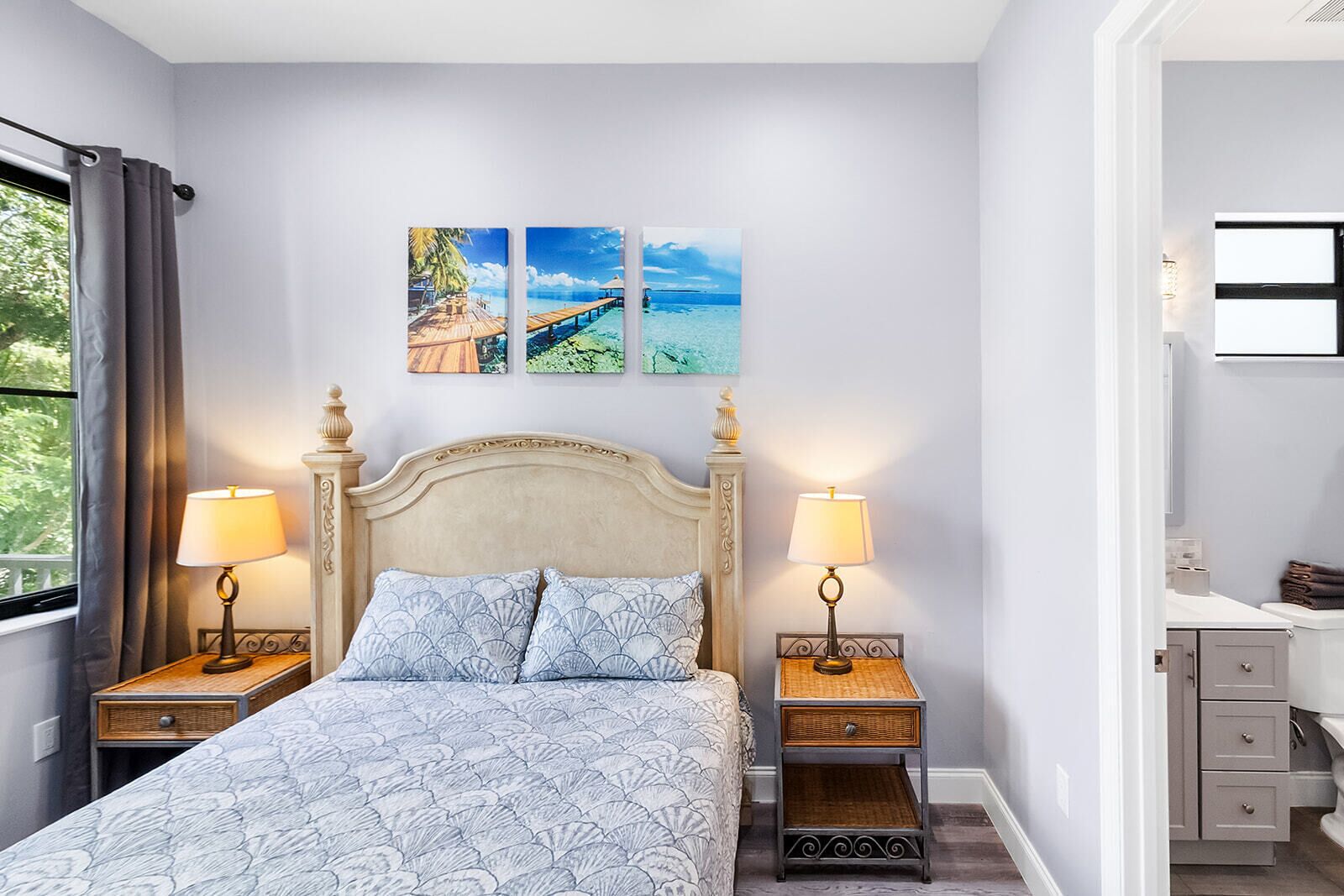 Ein Schlafzimmer mit einem Bett, zwei Nachttischen, einem Kopfteil und drei an der Wand befestigten Bildern.