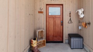 Una puerta de madera con el número 3499, una decoración de cráneo de caballo y una maleta negra pequeña.