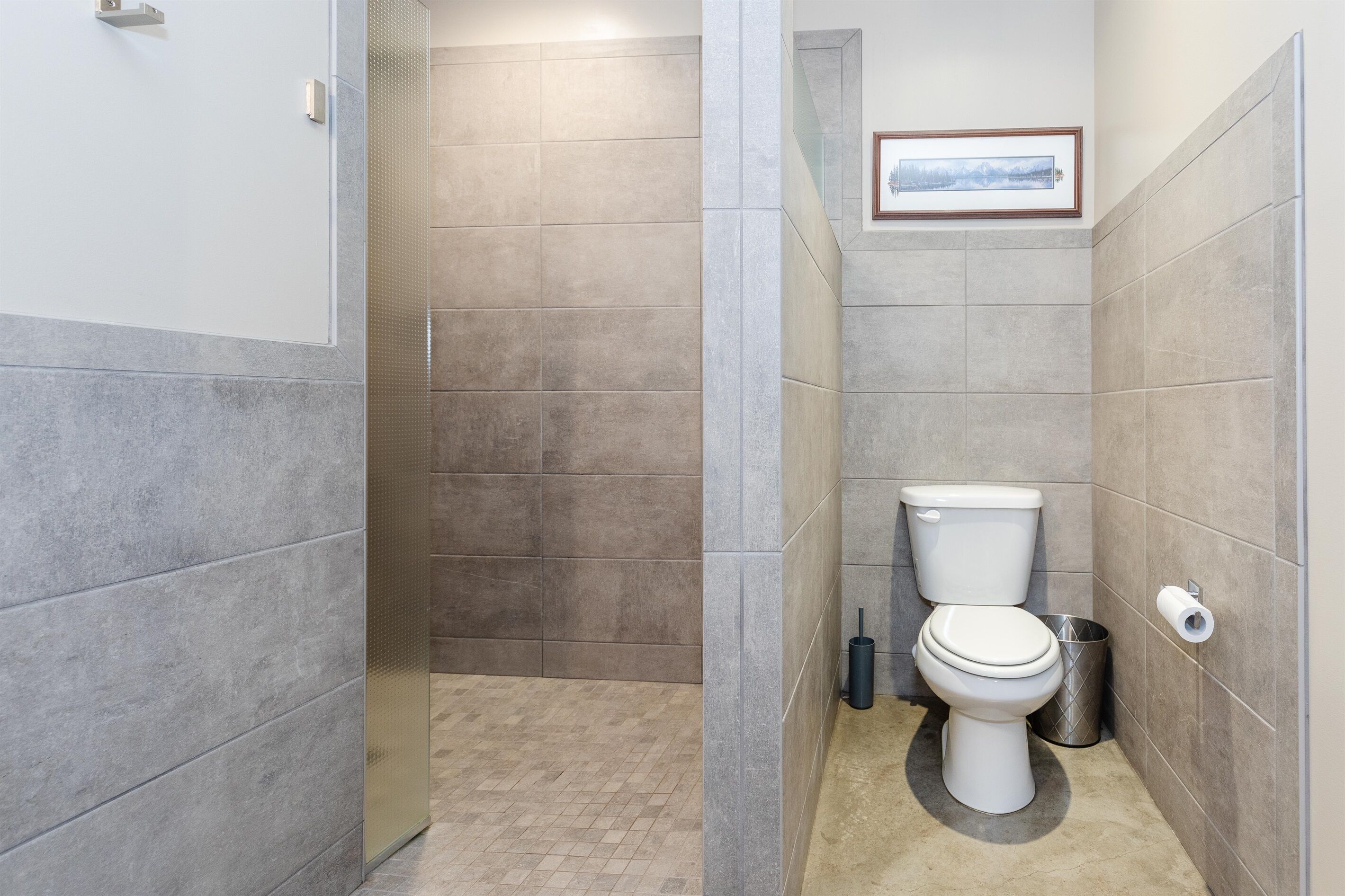 Une salle de bain avec des toilettes, une douche et des murs carrelés.