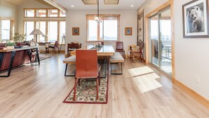 Un vaste espace dédié à la salle à manger, avec une grande table en bois, de nombreuses chaises et une vue sur les montagnes grâce à de grandes fenêtres.