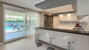 A modern kitchen with a glass door leading to a pool area. - Amazing home in Porec (Porec)