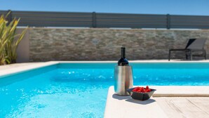A swimming pool with a bottle and a bowl of strawberries on the edge. - Amazing home in Porec (Porec)