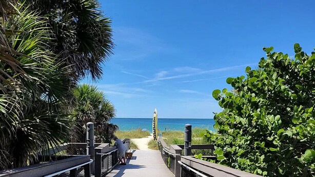 A wooden boardwalk leading to a beach with palm trees and a clear blue sky. - Casey Key/Nokomis Florida home, minutes to the beach (Nokomis)
