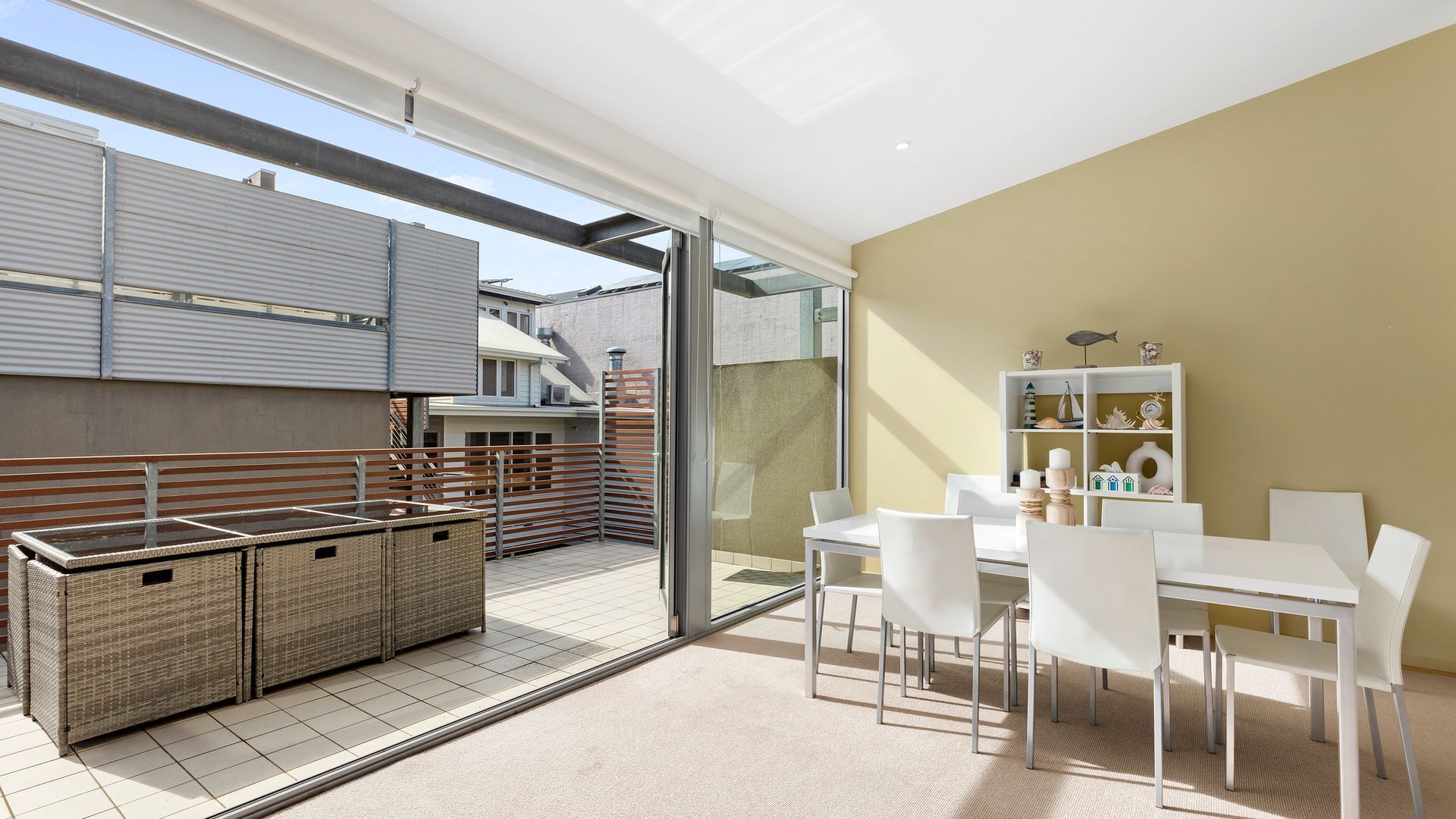 Eine moderne Außenpatio mit Essbereich, Korbmöbeln und einem weißen Tischset.