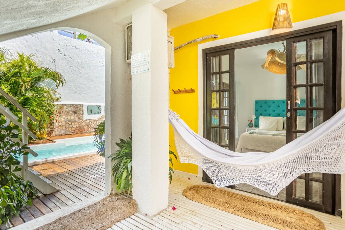 Ein Zimmer mit Hängematte, Pool und Blick auf eine Steinmauer und Grünpflanzen.