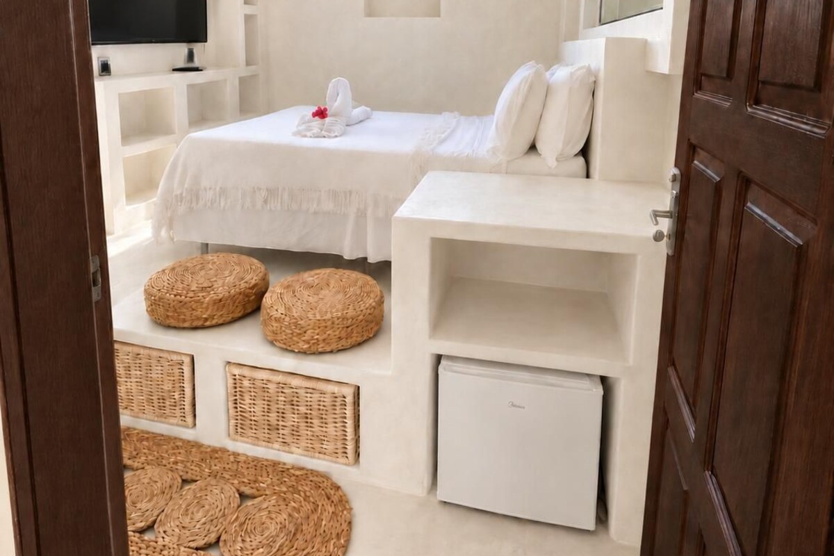 Une chambre avec un lit, une télévision, une armoire et des paniers en osier posés sur le sol.