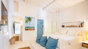 A bright, white room with a bed, a sofa, and a painting of a beach scene. - Pousada Duna Beach (Jijoca de Jericoacoara)
