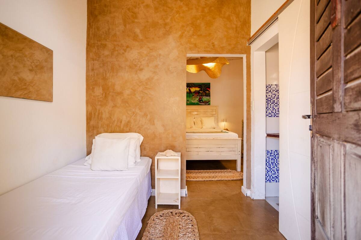 Ein Schlafzimmer mit einem Einzelbett, einem Nachttisch, einem kleinen Tisch und einem Gemälde an der Wand.