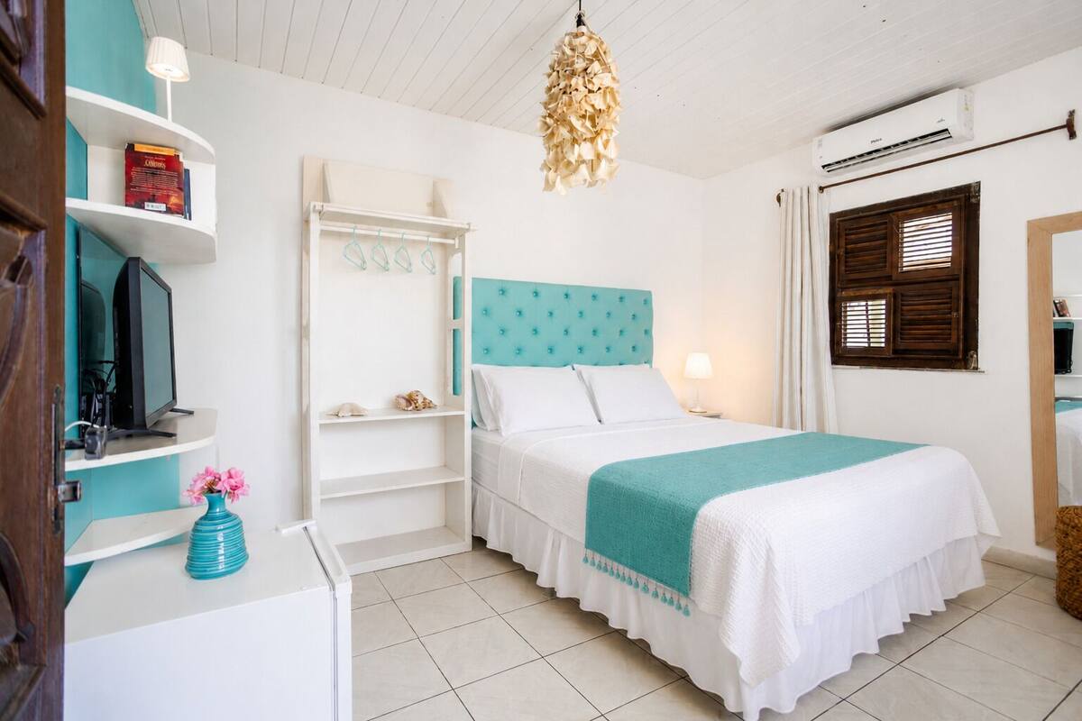 Ein Schlafzimmer mit einem Bett, einem Fernseher, einem Bücherregal und einer Pendelleuchte.