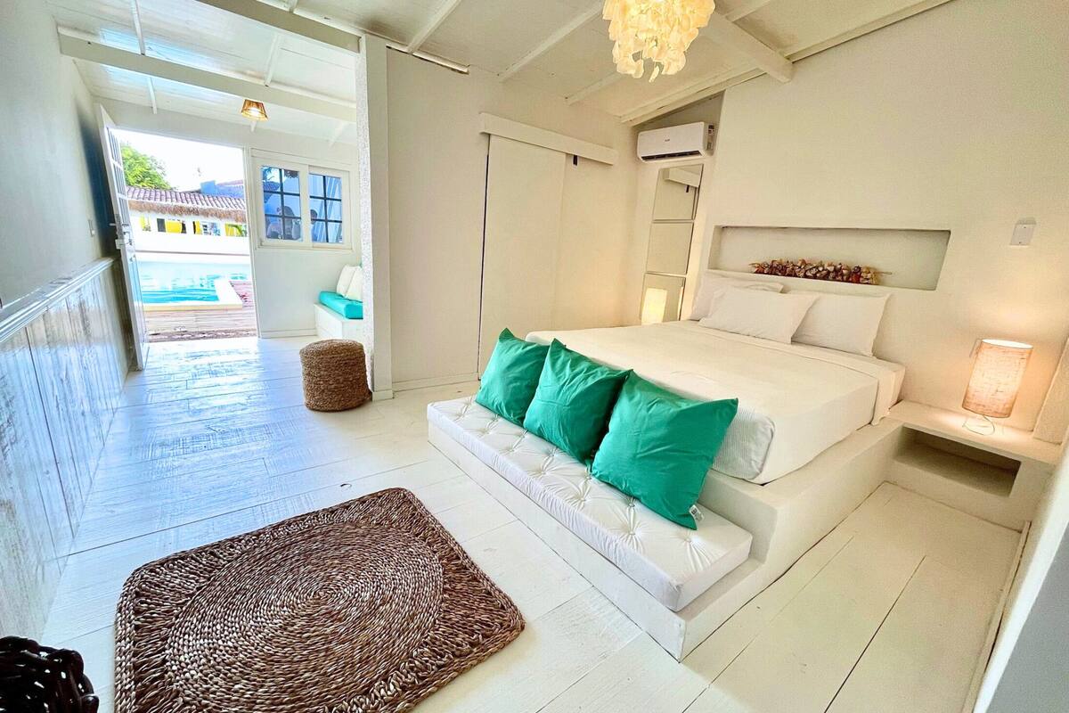 Ein Schlafzimmer mit Bett, Nachttisch, Pendelleuchte und Blick ins Freie.