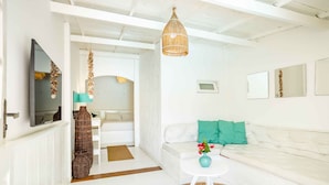 A bright, modern living room with a white sofa, a small round table with a vase, and a hanging light fixture. - Pousada Duna Beach (Jijoca de Jericoacoara)
