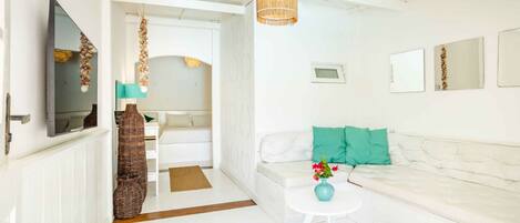 A bright, modern living room with a white sofa, a small round table with a vase, and a hanging light fixture.