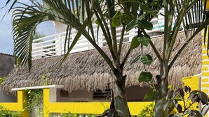 A sign for 'Pousada & Chalet Duna Beach Jericoacoara' with a thatched roof structure and yellow walls in the background. - Pousada Duna Beach (Jijoca de Jericoacoara)