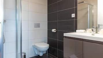 A modern bathroom with a glass shower enclosure, a toilet, and a vanity with a mirror.