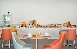 A breakfast buffet with various food items and beverages, arranged on a table with colorful chairs. - Villa Thermae Nancy (Nancy)