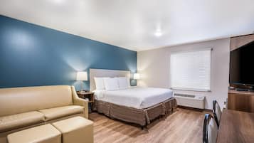 Een hotelkamer met een bed, een sofa, een bureau en een raam met jaloezieën.