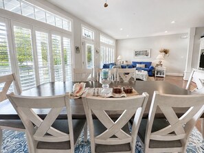 A dining area with a table set for four, surrounded by white chairs.