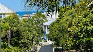 Eine Küstenstraße gesäumt von üppigem Grün und Gebäuden, die zu einem Strand führen.