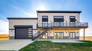 Ein modernes, zweistöckiges Haus mit Garage, Balkon und Treppe zum Obergeschoss.
