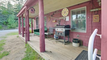 A rustic cabin with a porch, a grill, and a welcome sign.