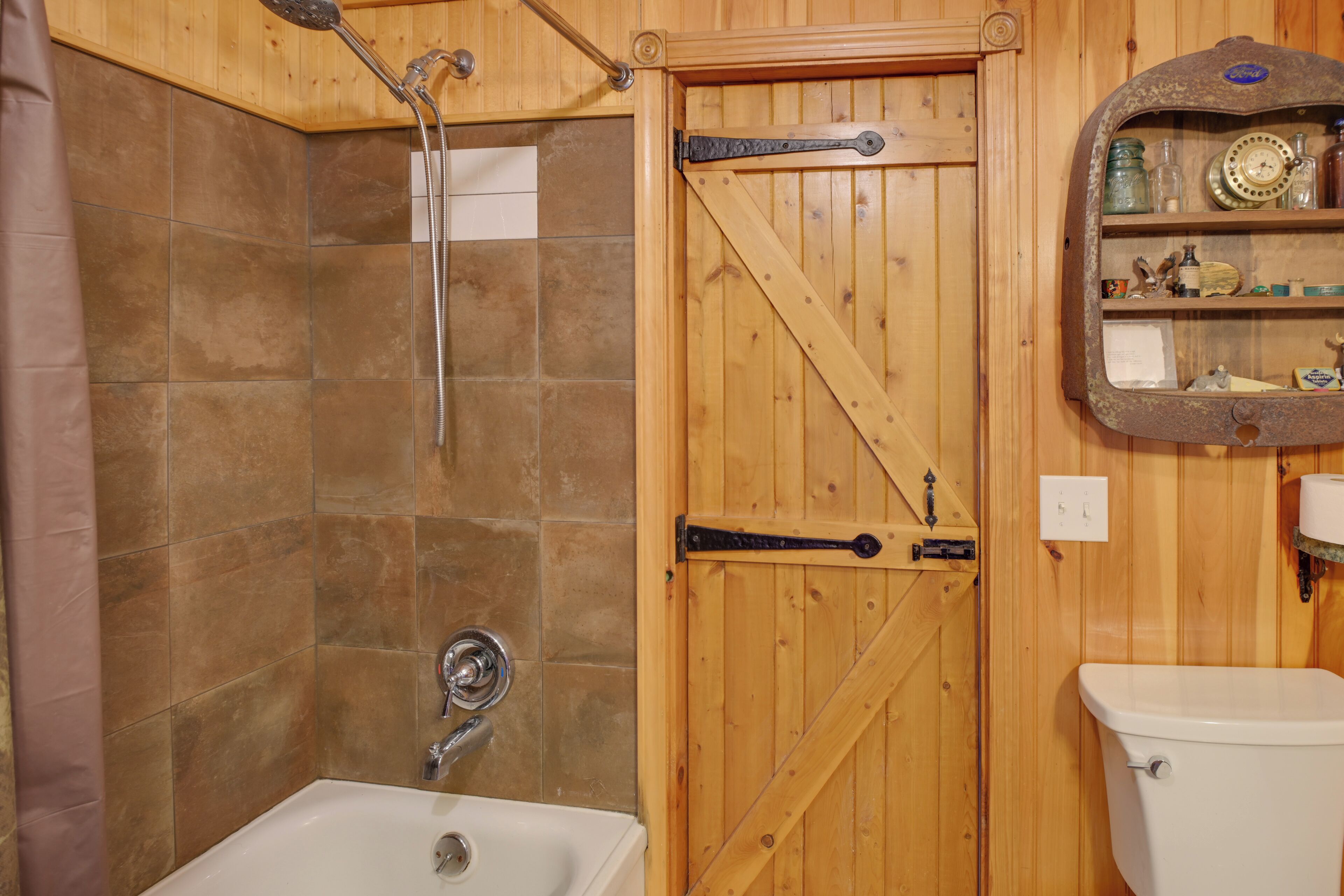 Une salle de bain avec une porte en bois, une douche et un lavabo.