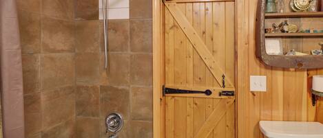 Une salle de bain avec une porte en bois, une douche et un lavabo.