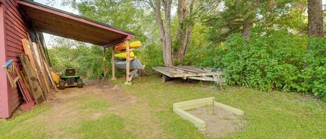 A covered outdoor area with a lawn, a wooden structure, and a pile of materials.