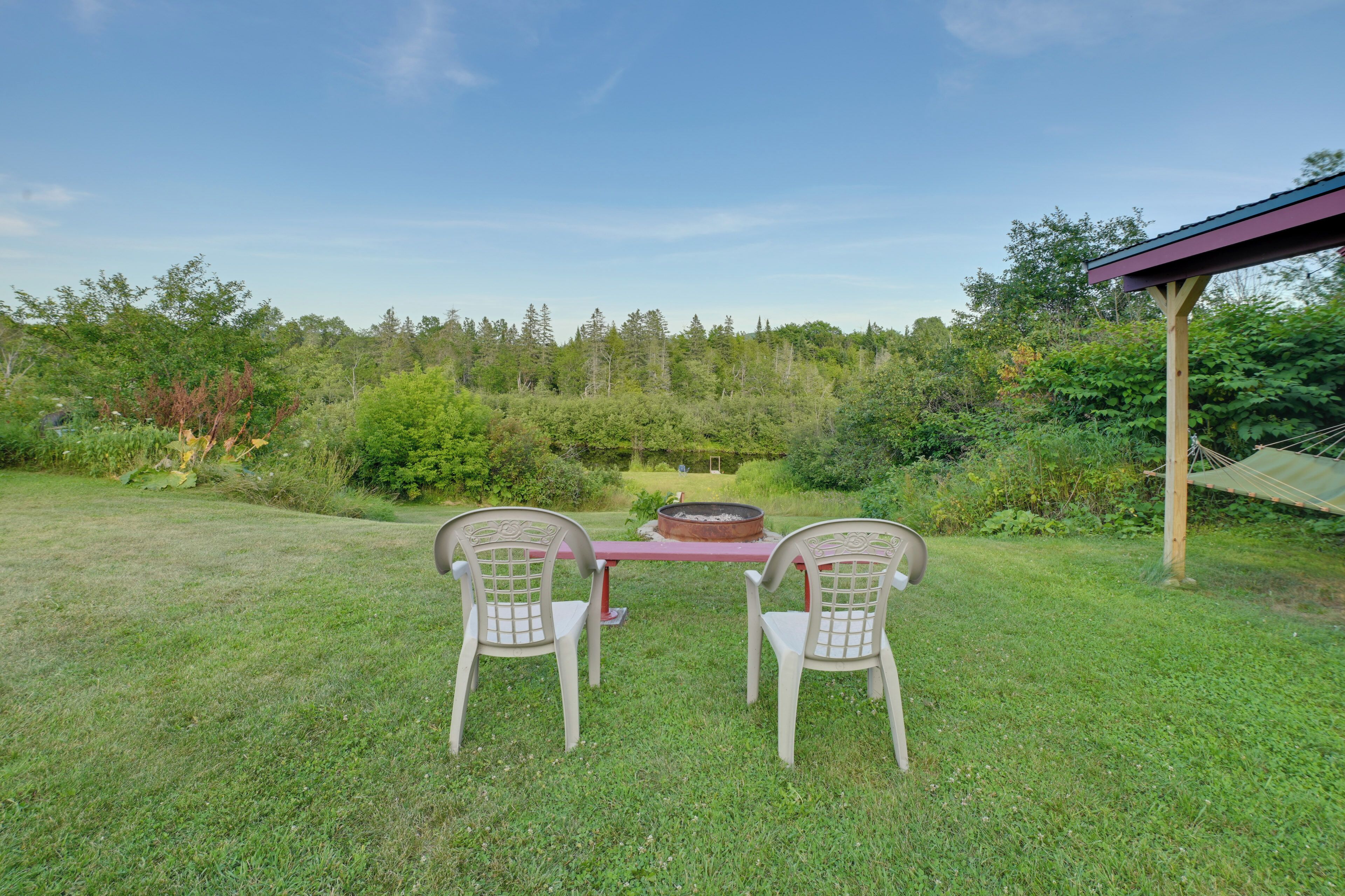 A picnic table with two chairs in a grassy area with a forest backdrop.