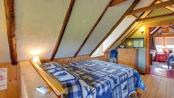 A bedroom with a wooden ceiling, a bed with a quilt, a nightstand, and a dresser.