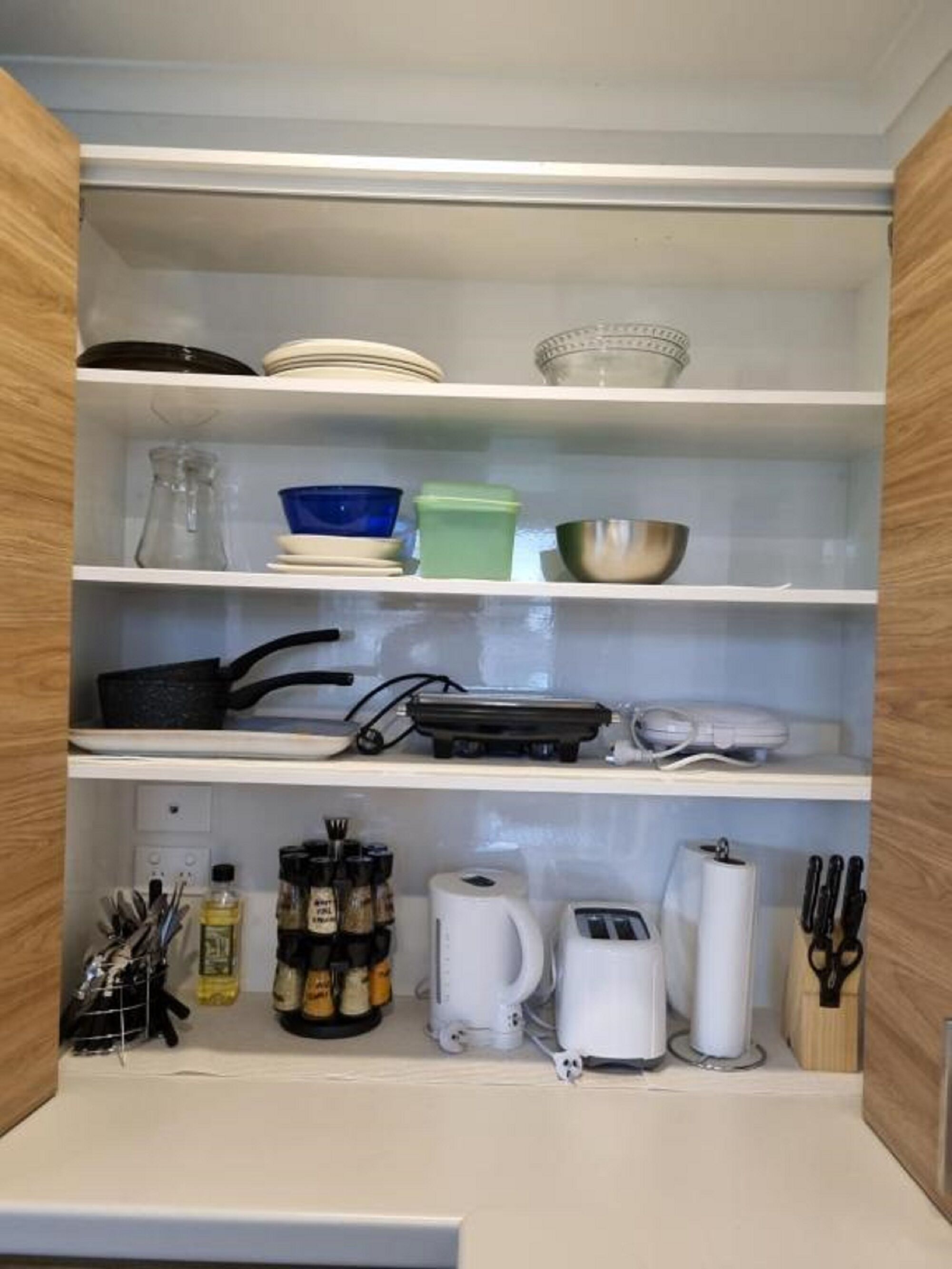 A kitchen with white shelves, a coffee maker, a toaster, and various kitchen utensils.