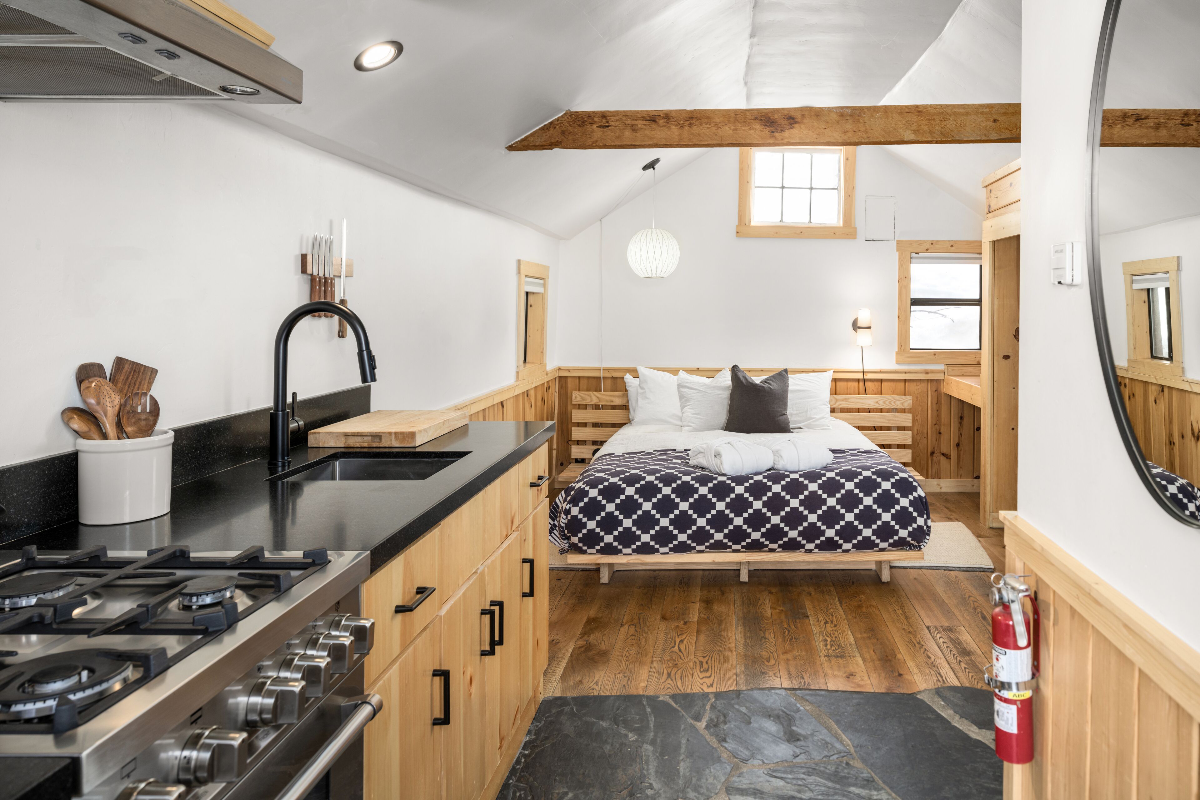 A compact, modern kitchen with a gas stove, wooden cabinets, and a black countertop.