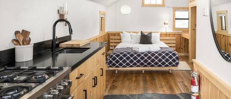 A compact, modern kitchen with a gas stove, wooden cabinets, and a black countertop.