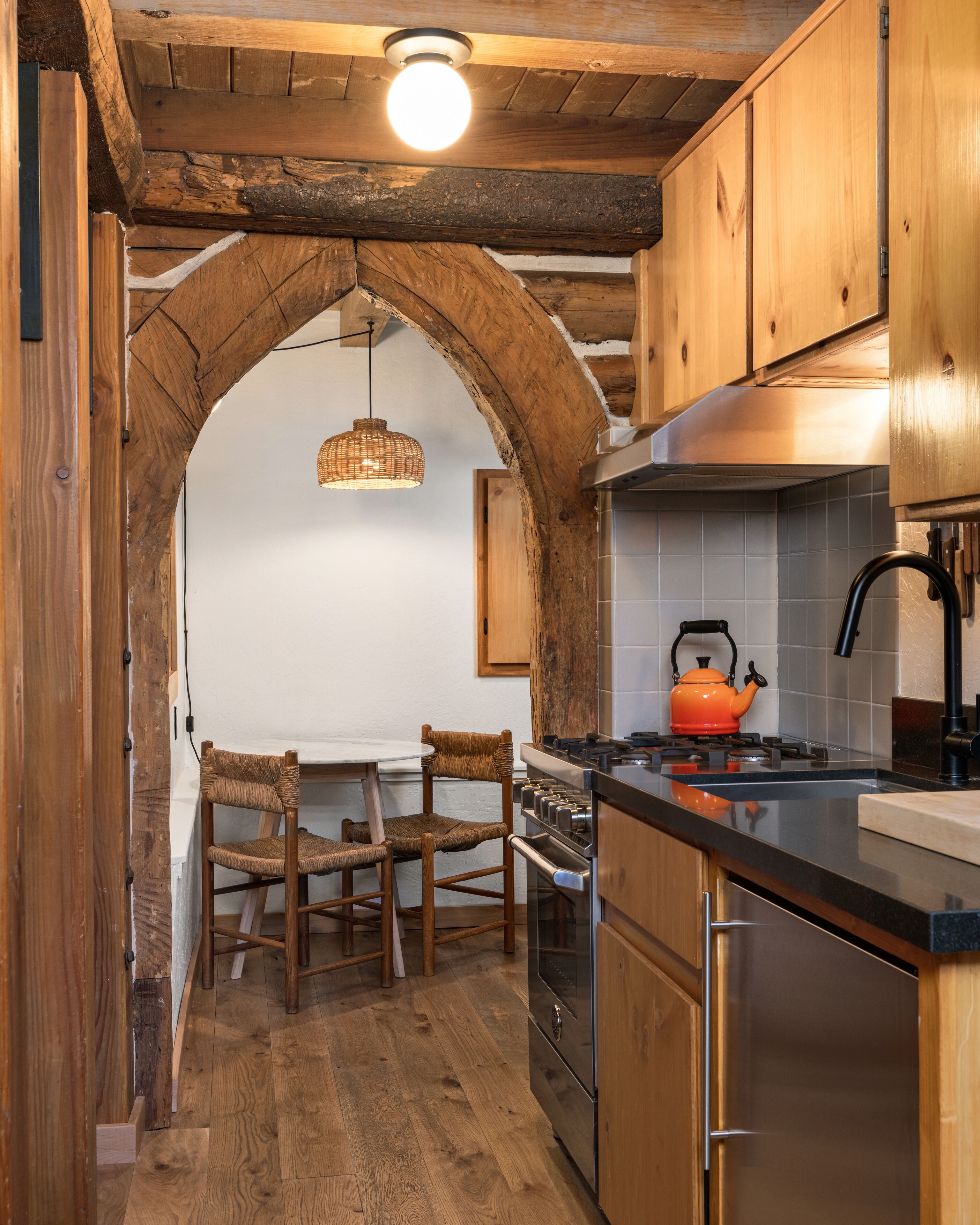 A kitchen with wooden cabinets, a gas stove, and a hanging light fixture.