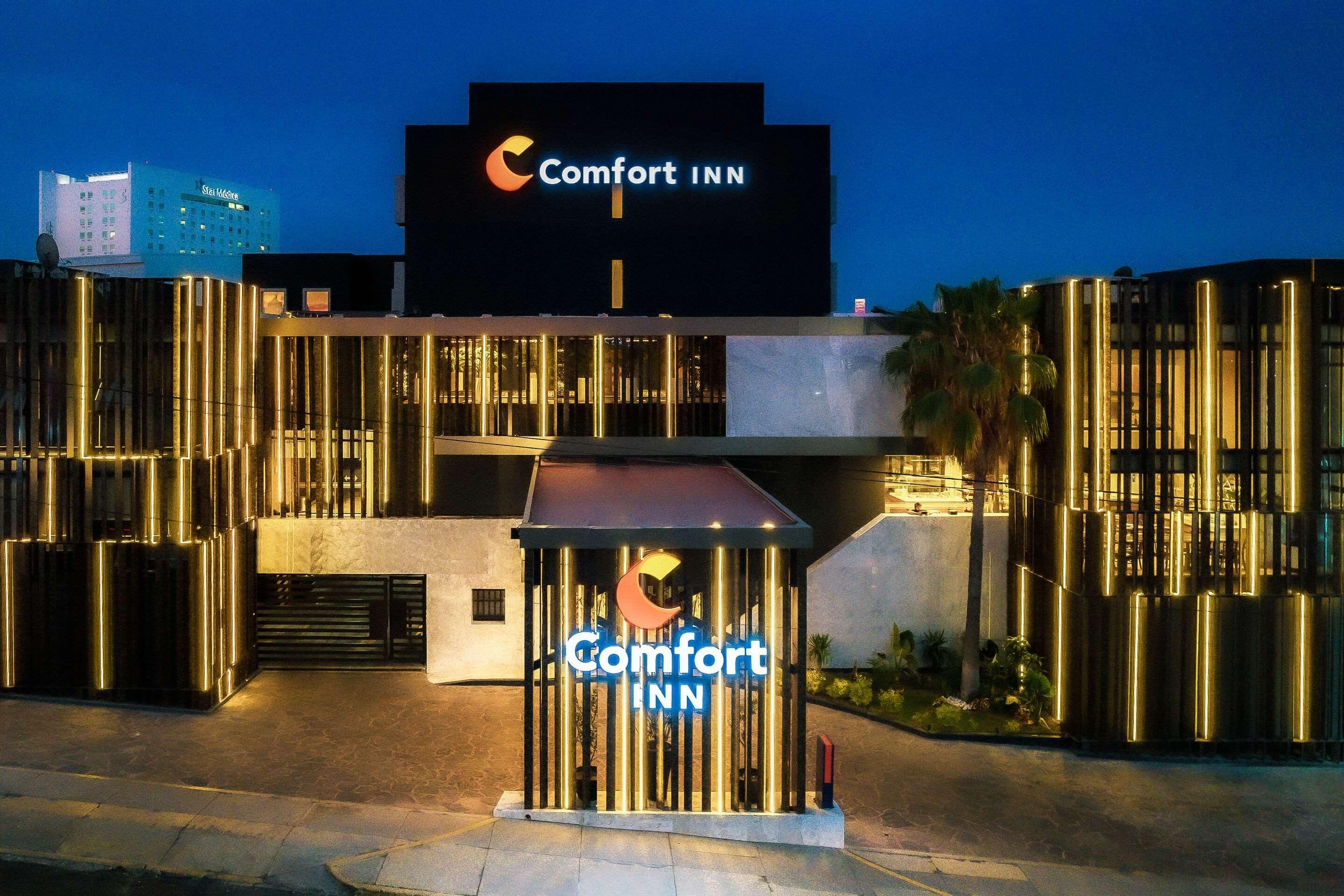 Entrada de un hotel Comfort Inn con un letrero llamativo, arquitectura moderna y fachada bien iluminada.