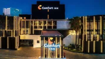 Entrada de un hotel Comfort Inn con un letrero llamativo, arquitectura moderna y fachada bien iluminada.