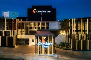 A Comfort Inn hotel entrance with a prominent sign, modern architecture, and a well-lit facade.