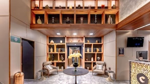A lobby with a reception desk, seating area, and shelves with decorative items. - Comfort Inn Queretaro Tecnologico (Querétaro)