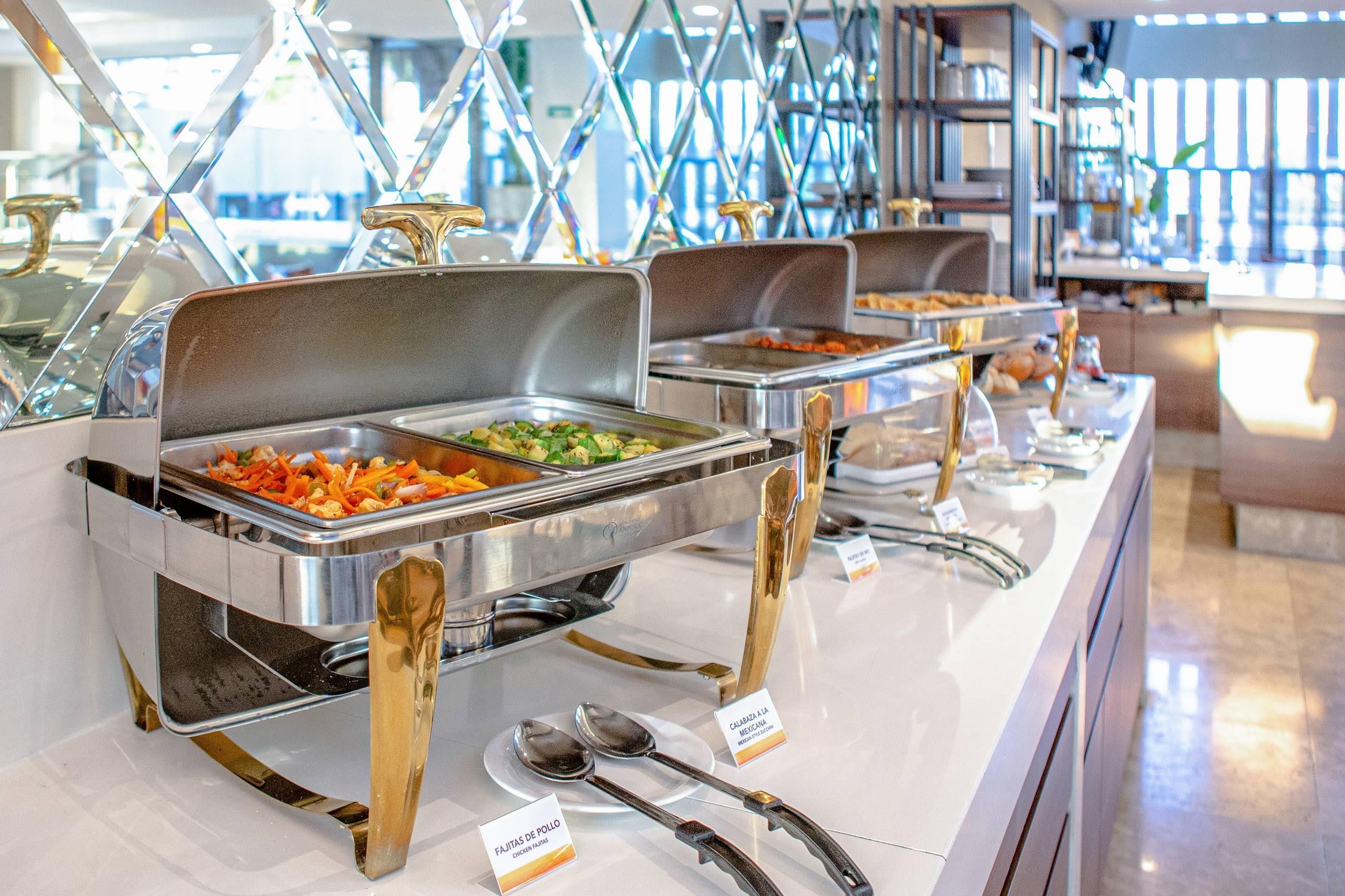 A buffet setup with multiple serving stations, each with a metal tray and a spoon.