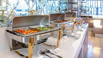 A buffet setup with multiple serving stations, each with a metal tray and a spoon.