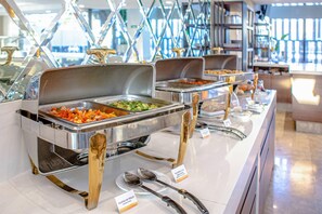 A buffet setup with multiple serving stations, each with a metal tray and a spoon.