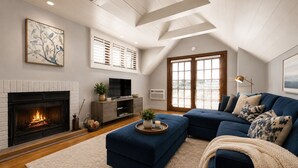 Una sala de estar con chimenea, un sofá grande y un televisor.