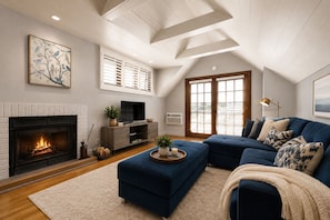 A living room with a fireplace, a large sofa, and a television. - The De La Vina Inn (Santa Barbara)