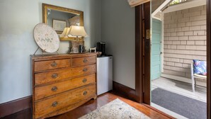 A wooden dresser with drawers, a mirror with a gold frame, a lamp, and a coffee maker. - The De La Vina Inn (Santa Barbara)