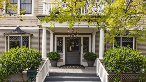 A two-story house with a front porch, a black front door, and a chandelier. - The De La Vina Inn (Santa Barbara)
